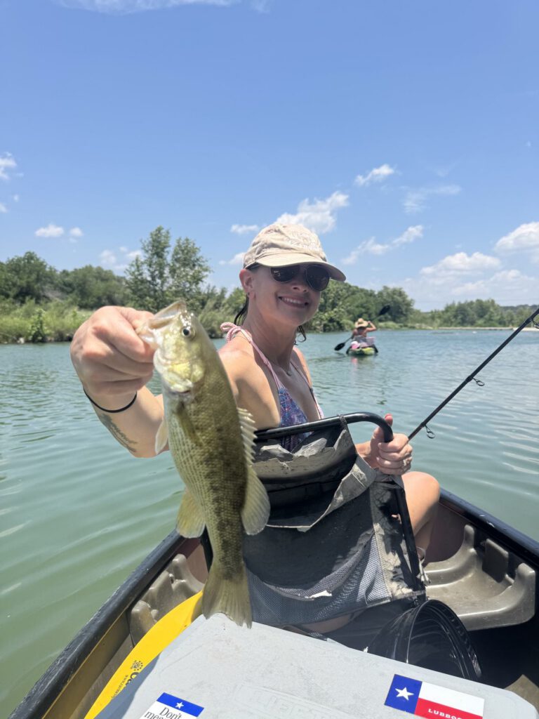 Angler holding a bass from a fishing kayak on open water