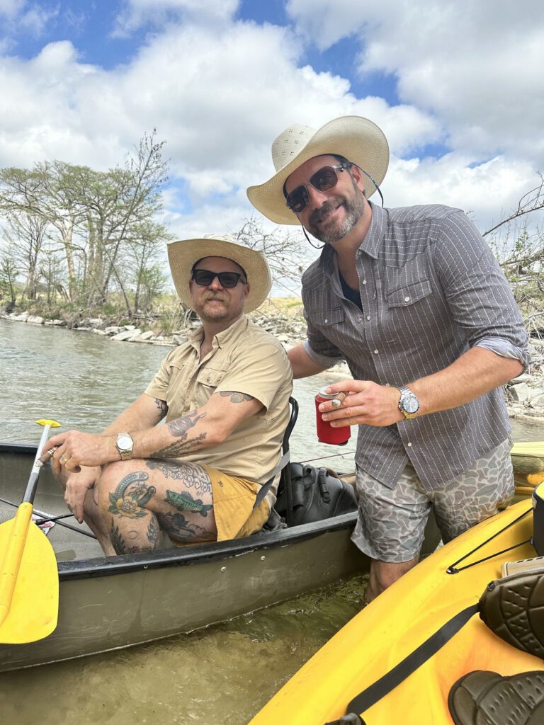Two paddlers pausing in a canoe on a tree-lined river