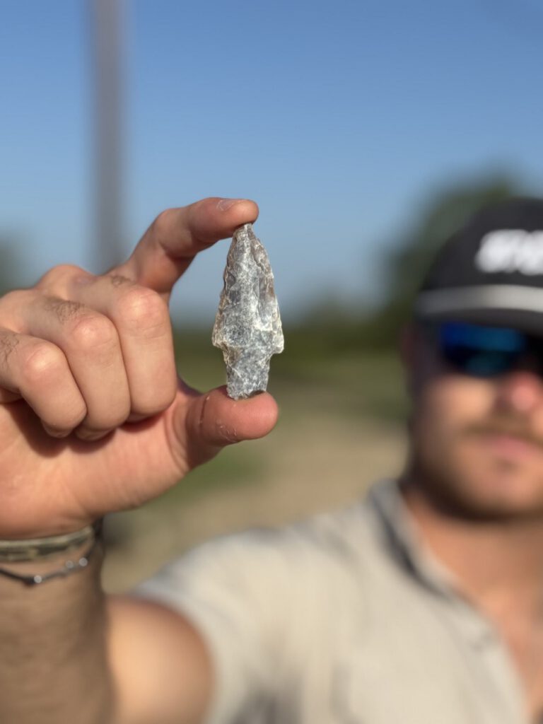 Hand holding a small worked stone point outdoors