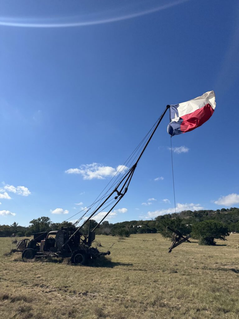 Texas flag flying beneath a clear blue Hill Country sky
